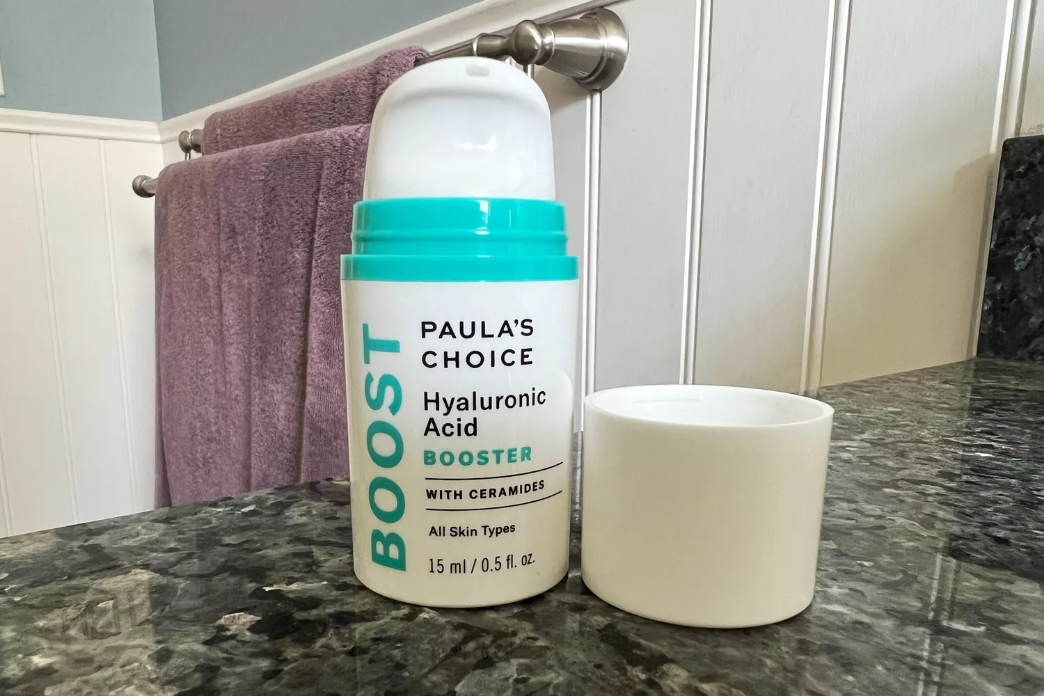 A bottle of Paula's Choice Hyaluronic Acid Booster with Ceramides on a bathroom counter